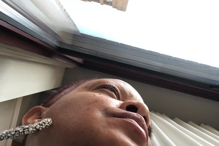 Low angle view of a woman wearing silver earrings looking out a window at a tall city building.