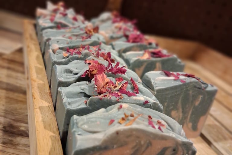 Handmade artisan soap bars with floral petals on a wooden tray for natural skincare.