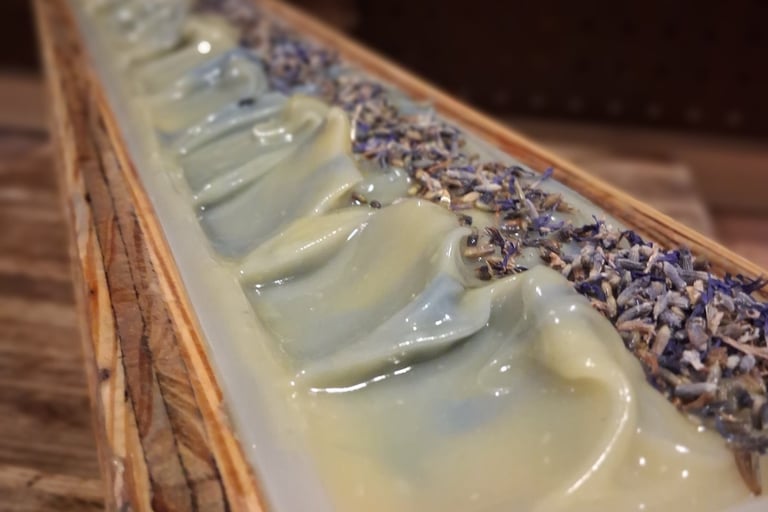 Handmade bluebird lane soap loaf in a wooden mold topped with dried botanical flower buds.