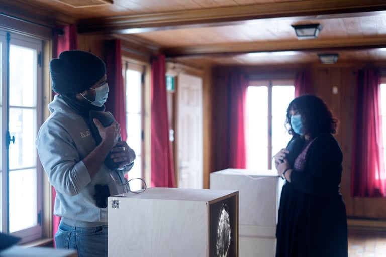 Two people hold vibrating cushions with brain waves in front of light boxes sharing MS stories.