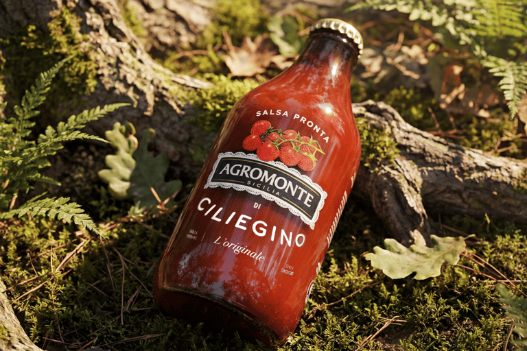 Bottiglia di Salsa Pronta di Ciliegino Agromonte con Etichetta della Terra in ambiente naturale