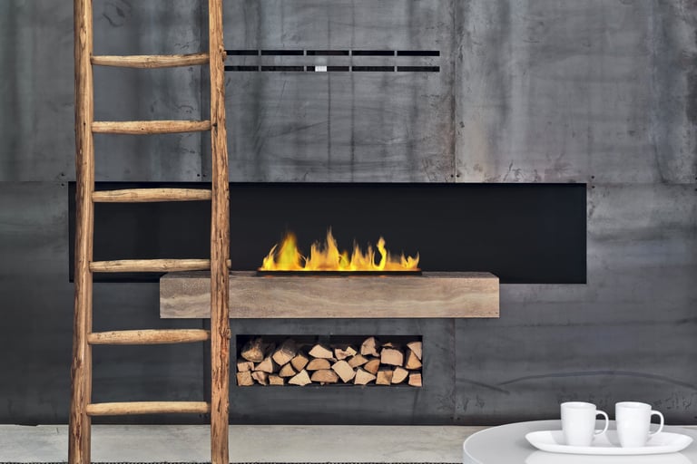 Camino moderno a parete su muro in cemento con legna a vista e scala in legno