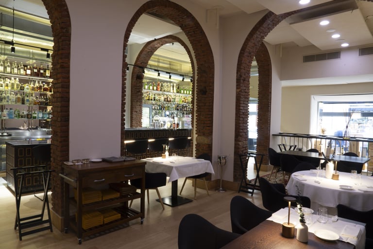 Sala principale del Quadri Bistrot a Milano con archi in mattoni e cocktail bar sullo sfondo