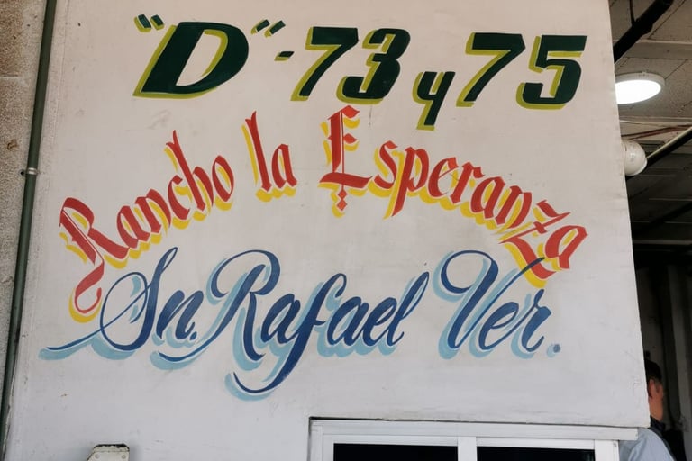 Letrero pintado en la pared de un negocio: "D-73, 75, Rancho la Esperanza, Sn. Rafael Ver