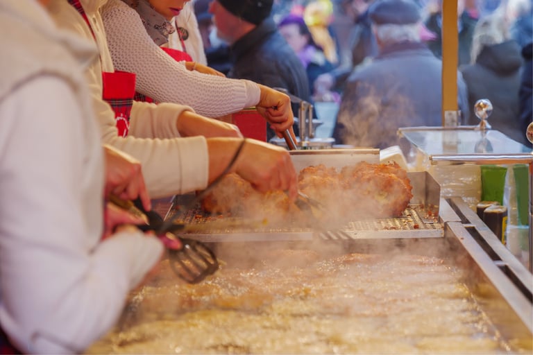Street food vendors frying crispy potato pancakes at a busy outdoor European Christmas market stall.