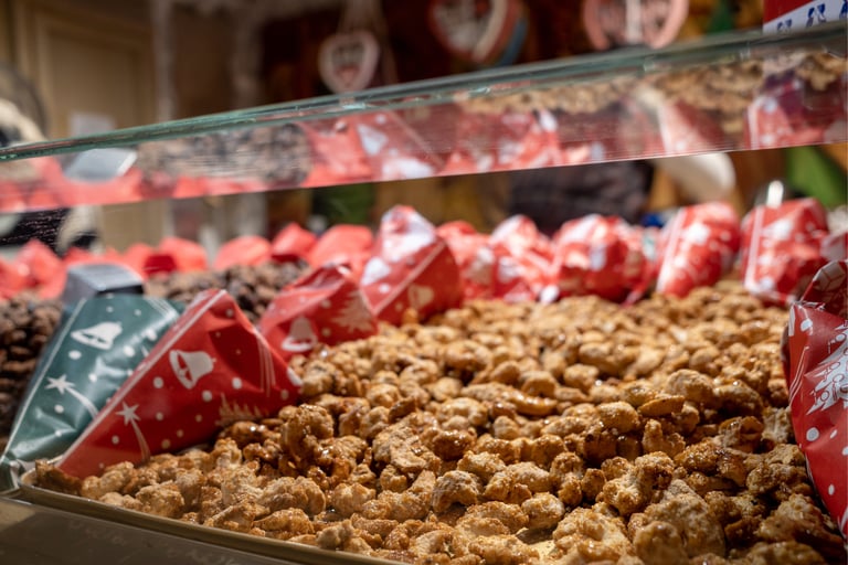 Roasted candied almonds and nuts displayed in festive paper cones at a traditional Christmas market stall.