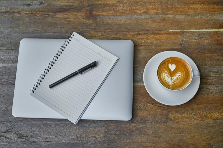 a cup of coffee and a notebook with a pen on wooden table