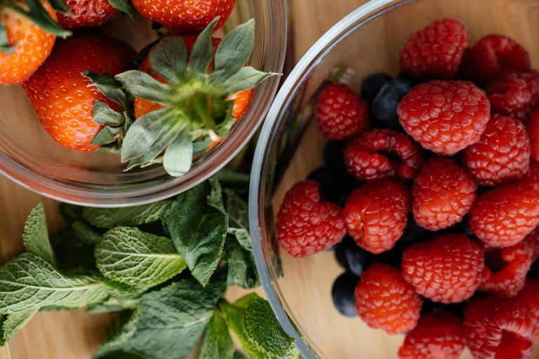 Strawberries with raspberries and blueberries in separate glass bowls
