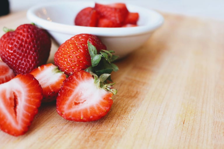 Whole and sliced strawberries in white bowl on table