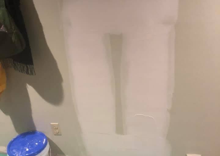a bucket of joint compount on the floor of a room in front of a drywall repair