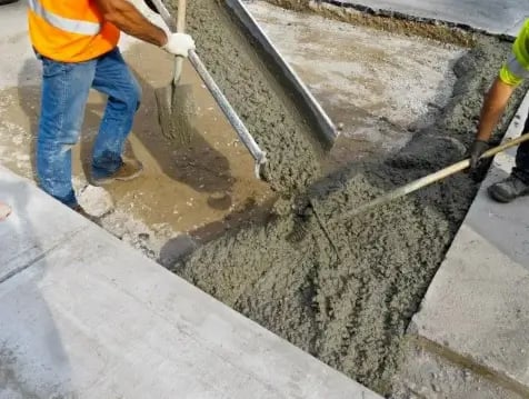 a man is laying concrete on the sidewalk