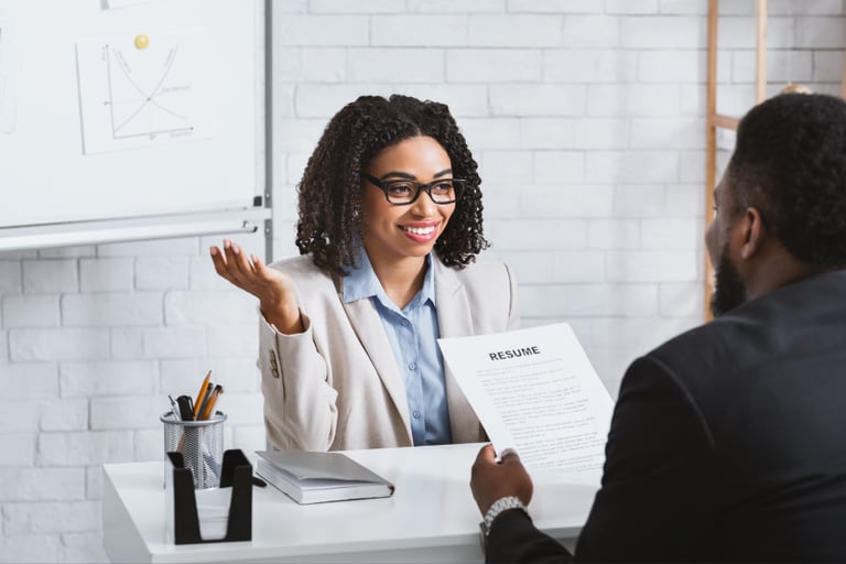 a recruiter in a business suit sitting at a desk interviewing a candidate