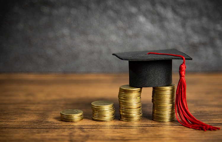 a graduation cap with a graduation cap on top of a stack of coins