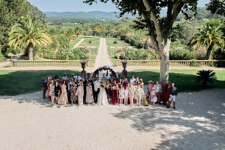 Group photo of wedding guests in the garden of a French château during an American wedding