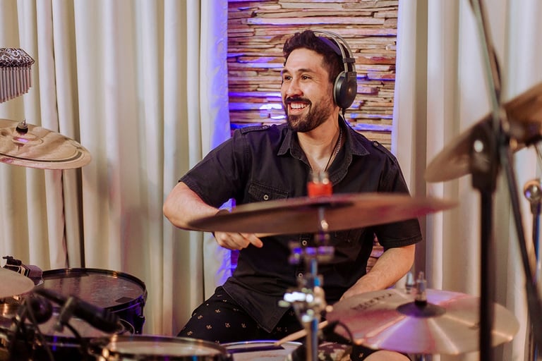 Drummer Lucas Dias playing the drums while wearing headphones.