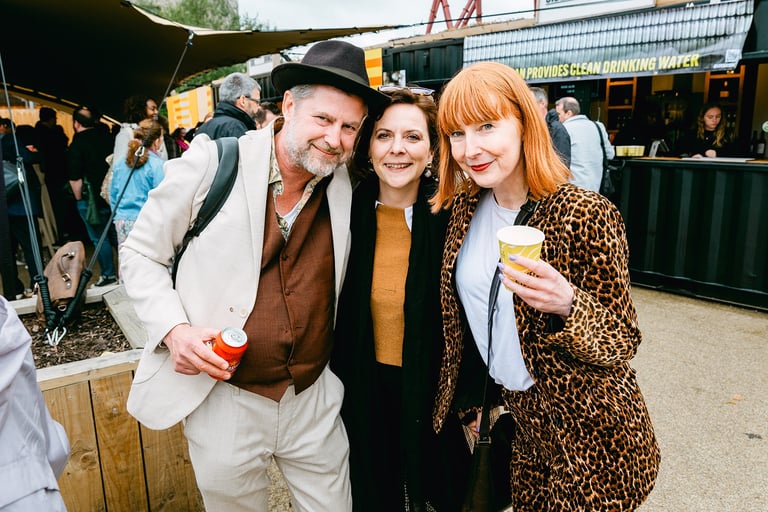Three people smile at the camera. They are at a work conference at Riverside Park London