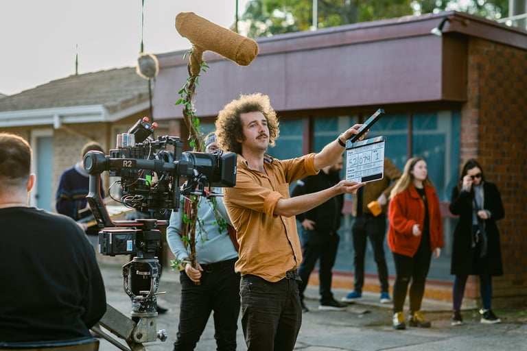 Director Tim Carlier stands with a clapper board in front of a camera on his shor film set 'Parco'