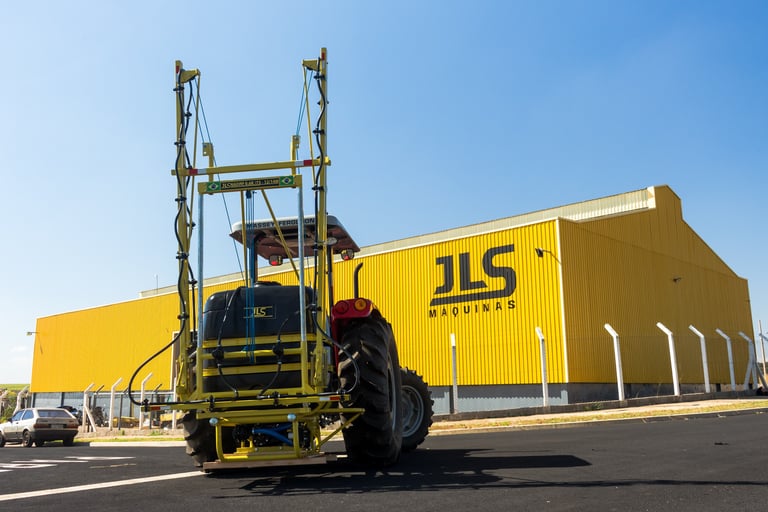 Pulverizador agrícola JLS Nadja 0.6k com a fábrica da JLS ao fundo