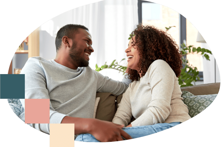 a man and woman sitting on a couch laughing with each other
