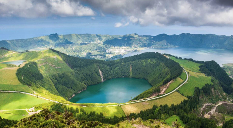 A picture of the top of a volcano with a road and fields around it.