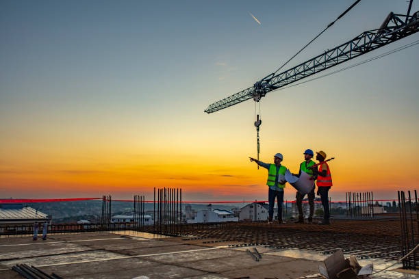 roofing workers pointing into the distant sunset on a commercial roof