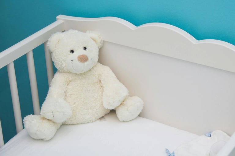 un lit bébé à barreaux et un doudou blancs dans une chambre aux murs bleus, pour une ambiance apaisante