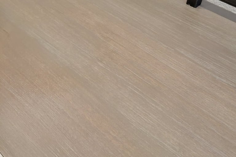 Close-up of a light brown weathered wood tabletop with visible grain.