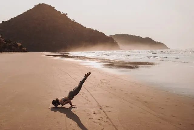 une femme faisant une posture de yoga à la plage