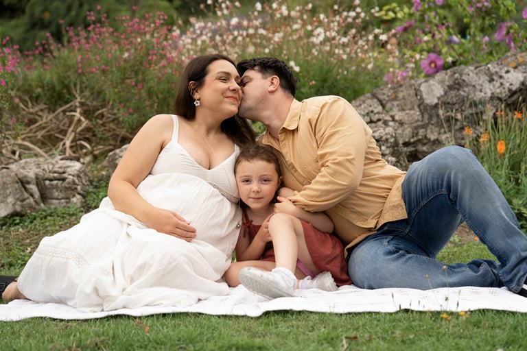 Pregnant mother holding her daughter and father kissing her cheek 