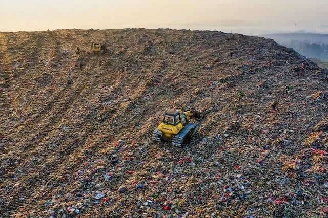 Aerial view of bulldozers managing waste at a large landfill site for environmental disposal.