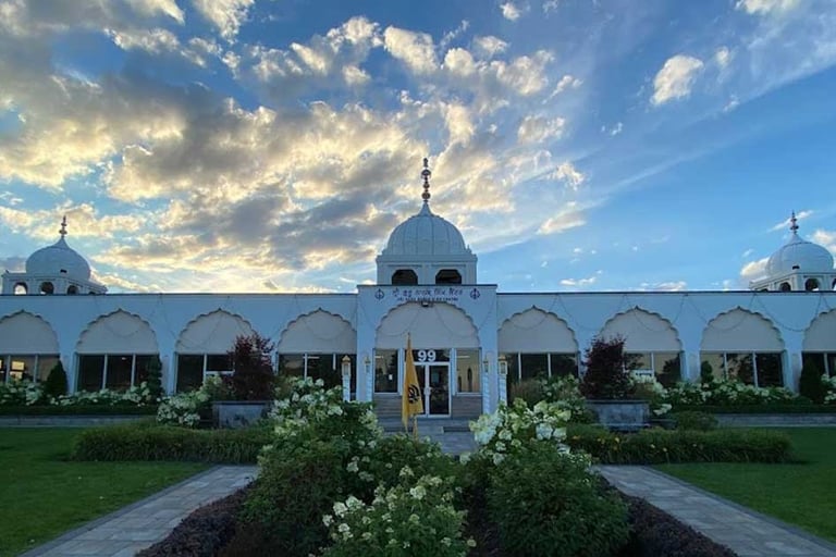 White Sikh Gurdwara temple with domed architecture and garden at sunset
