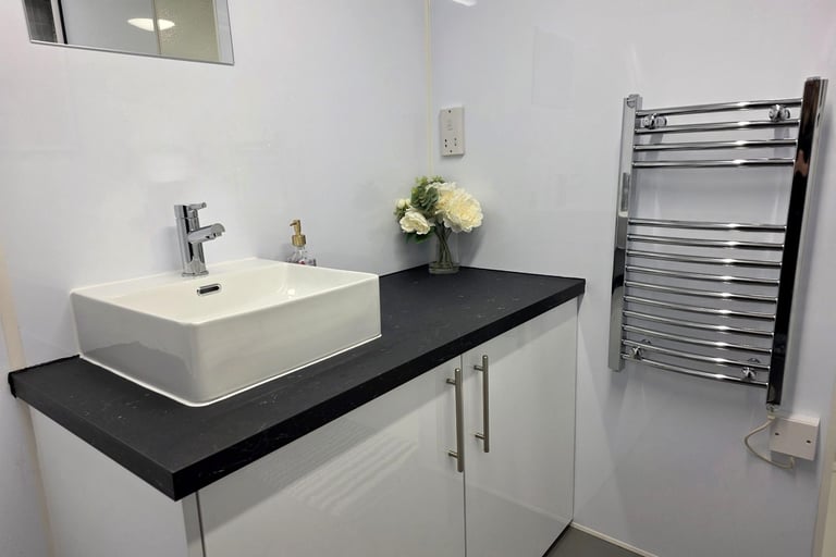 Vanity unit and towel rail inside a fully equipped temporary bathroom pod for renovation use.