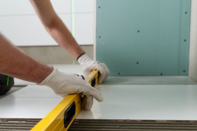 Installer wearing gloves using a yellow spirit level during shower installation
