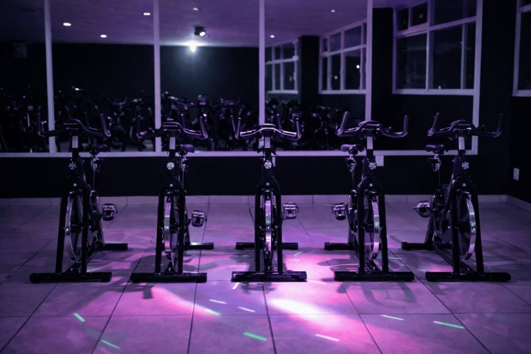 Fila de bicicletas estáticas en un moderno estudio de ciclismo int con iluminación ambiental mora