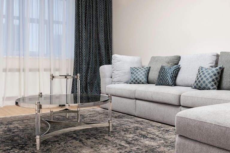 Gray sectional sofa styled with layered throw pillows in blue and gray patterns, patterned curtains,
