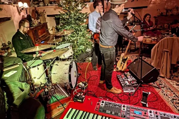 The full 4-piece Mosaic band performing live in a rustic barn venue with professional lighting