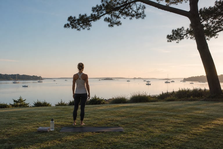 Une femme contemple le paysage du Golfe du Morbihan, debout sur une pelouse, au coucher du soleil.