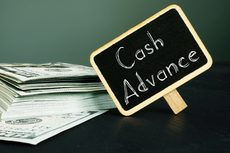 Chalkboard sign with words Cash Advance next to stack of bills
