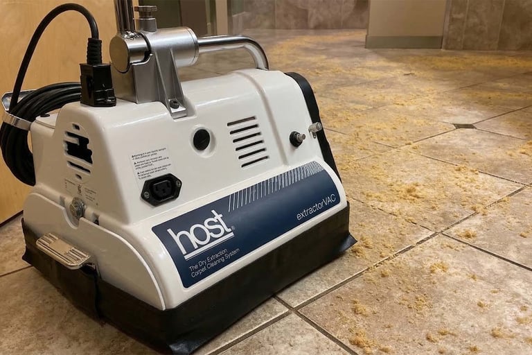 A professional-grade white Host ExtractorVAC machine cleaning loose, dirt-lifting compound from a tiled floor