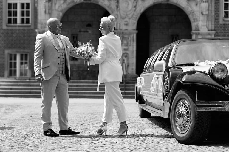 A bride and groom dancing next to a limousine.