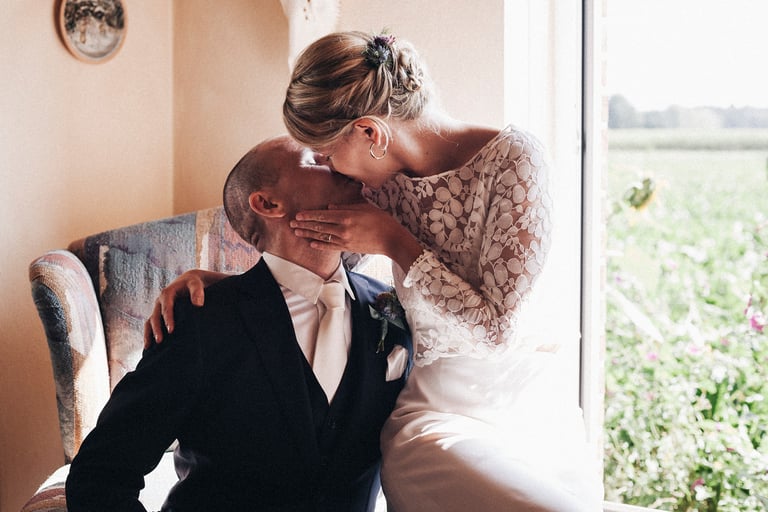 Bride and groom kissing on an armchair.