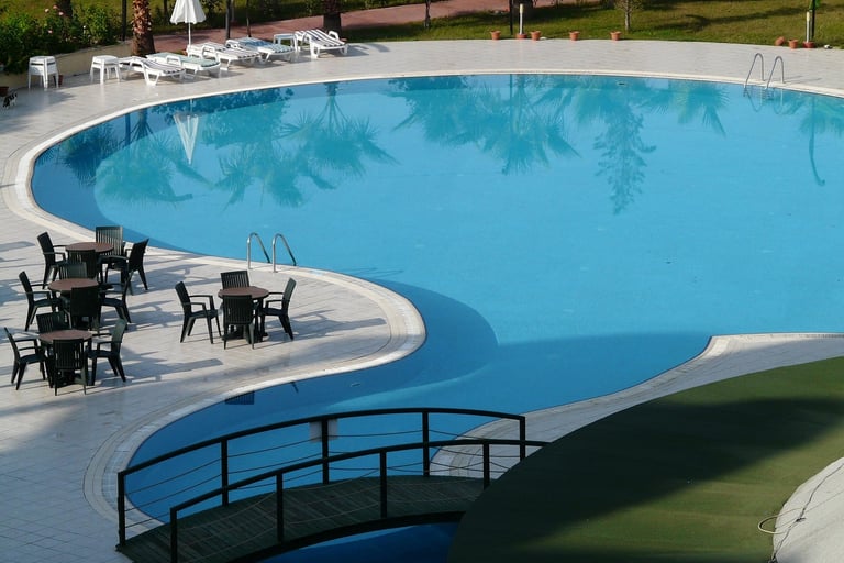 a pool with chairs and tables in a resort
