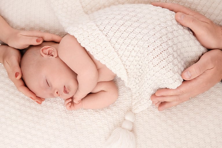 photo de bébé doucement enveloppé des mains de ses parents
