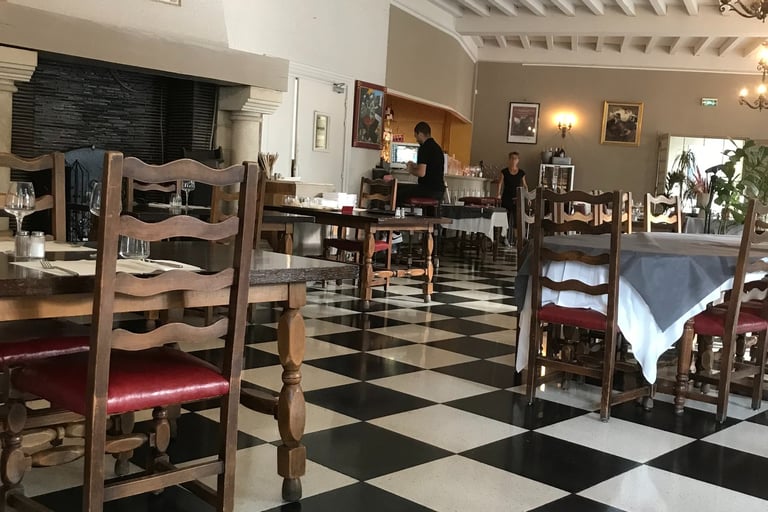 Rustic restaurant interior with black and white checkered floors, In Quillan.