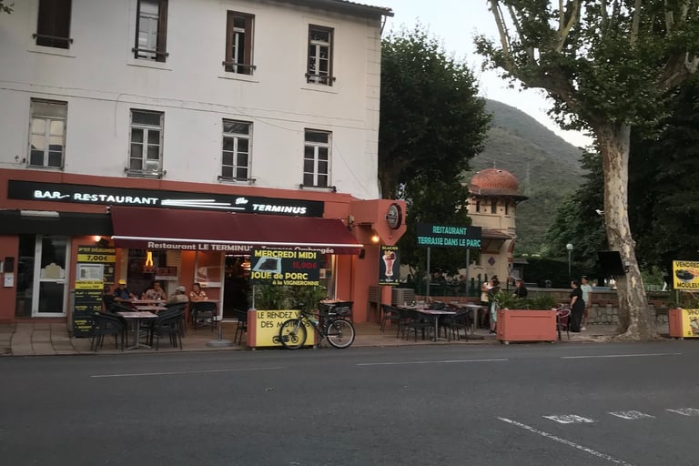Charming sidewalk terrace of Le Terminus French bar and restaurant in a scenic Quillan.