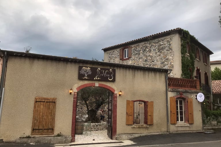Rustic French stone building and wine bar entrance with wooden shutters in Quillan.