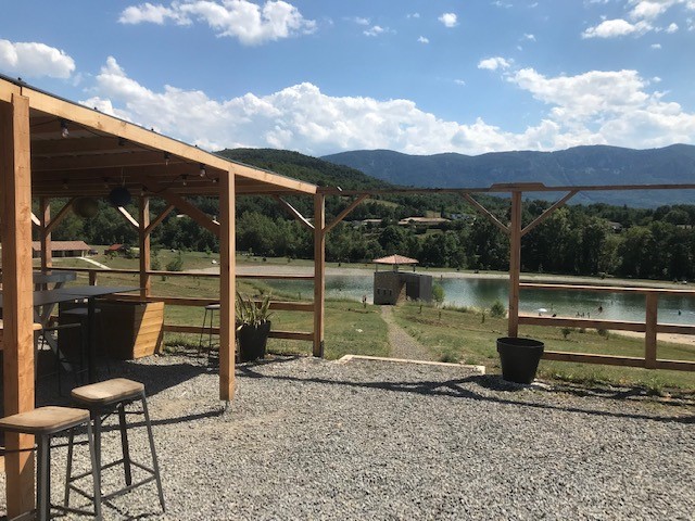 Rustic outdoor patio with wooden pergola overlooking a scenic lake and mountains in Quillan.