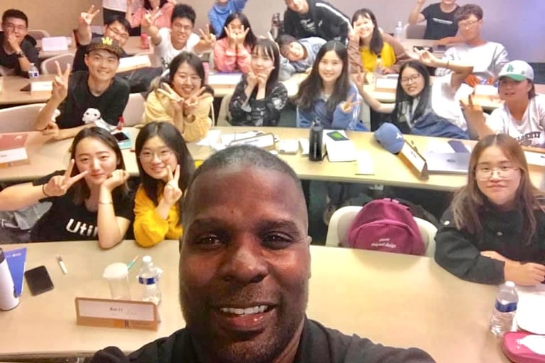 Dr. Marlon with his students seated holding up the peace sign