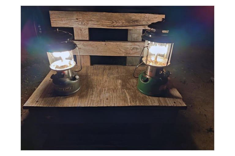 Two antique lanterns with thorium on top of a wooden bench.