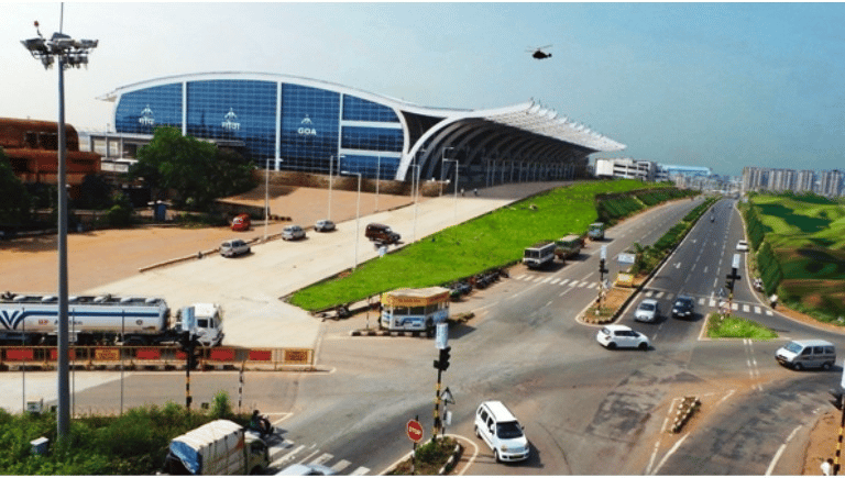 a goa airport terminal with a lot of cars moving in front of it